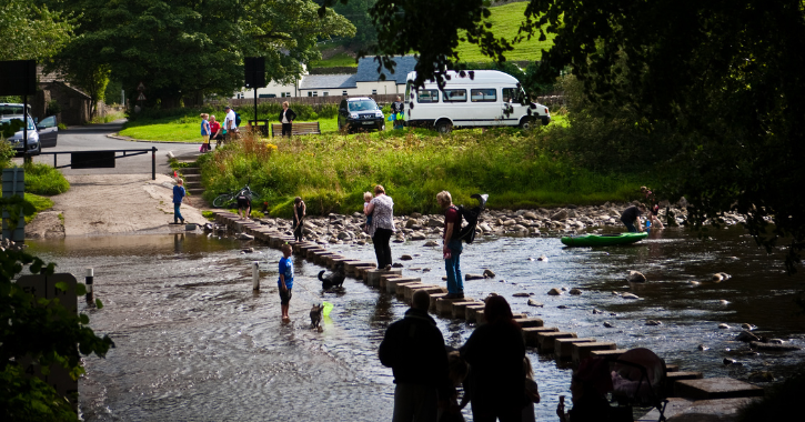 View of people crossing the stepping stones on a river in Stanhope.